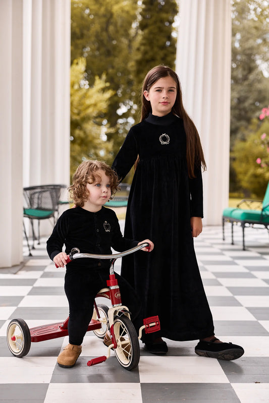 Black long robe with circular crest badge, worn by a child