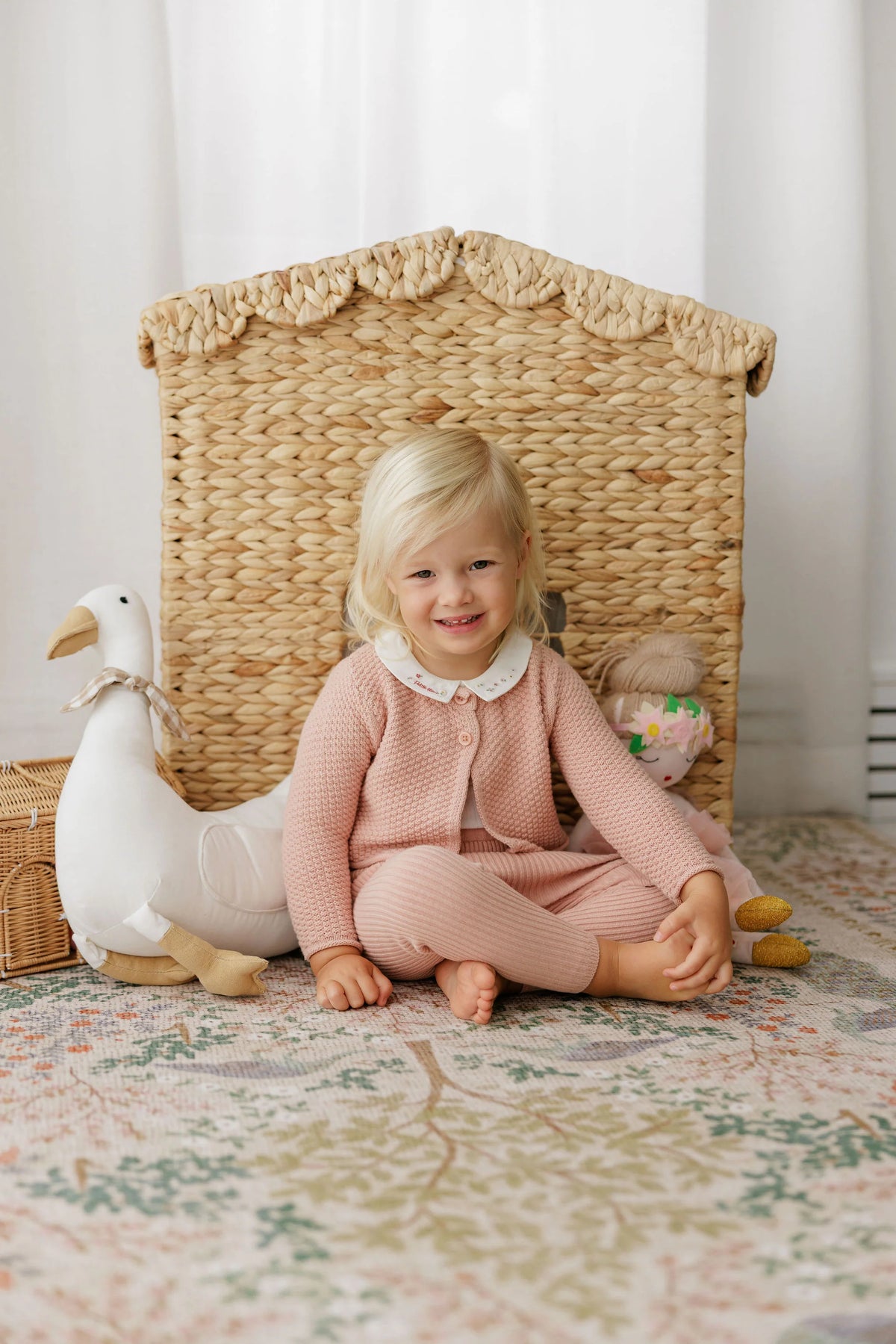Pink knit overalls on a child, with crossed back straps and long pant legs