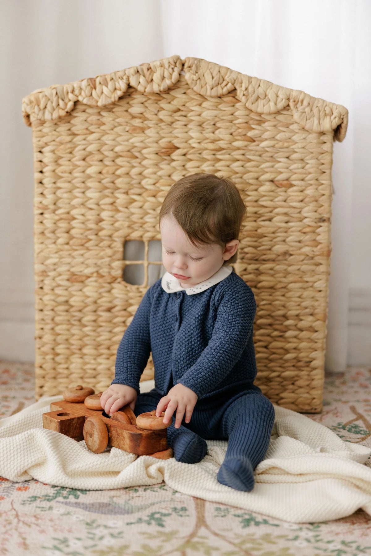 Navy knit overalls on a child, with crossed back straps and long sleeves