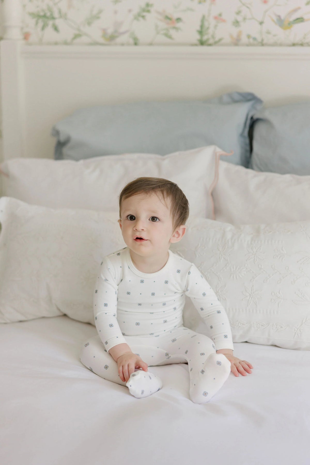 White long-sleeve footed romper with small geometric motifs on an infant